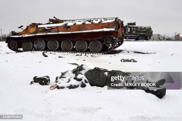The body of a Russian serviceman lies near destroyed Russian military vehicles on the roadside on the outskirts of Kharkiv on February 26 following...