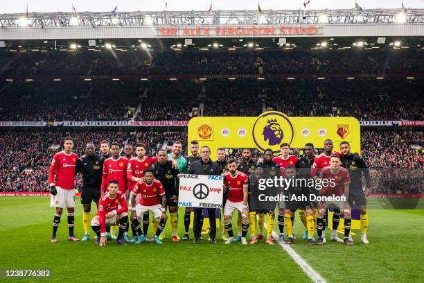 The Manchester United And Watford players line up with Manchester United Head Coach / Manager Ralf Rangnick and a banner for peace in Ukraine prior...