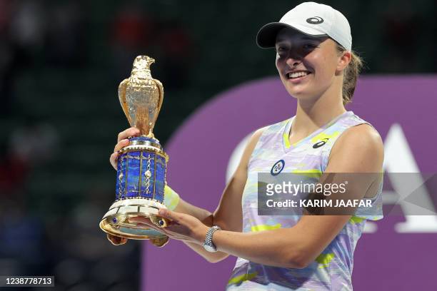 Iga Swiatek of Poland poses with the winner's trophy after winning the final match of the 2022 WTA Qatar Open in Doha on February 26, 2022.