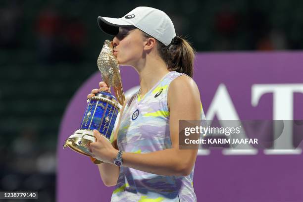 Iga Swiatek of Poland kisses the winner's trophy after winning the final match of the 2022 WTA Qatar Open in Doha on February 26, 2022.