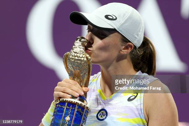 Iga Swiatek of Poland poses with the winner's trophy after winning the final match of the Qatar TotalEnergies Open at Khalifa International Tennis...