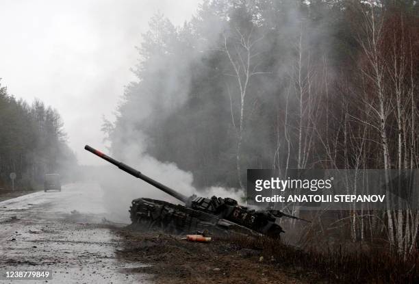 Smoke rises from a Russian tank destroyed by Ukrainian forces, on the side of a road in Lugansk region on February 26, 2022. - On February 26, Russia...