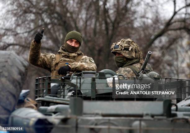 Ukrainian serviceman gives a thumb up riding atop a military vehicle before an attack in Lugansk region on February 26, 2022. - Russia on February 26...