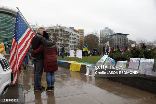 Couple holding an American flag embraces in the rain during a "Rally Against the War With Ukraine" event in Seattle, Washington on February 26, 2022....