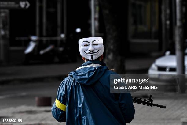 Member of Ukrainian forces, wearing Guy Fawkes mask , patrols downtown Kyiv, on February 27, 2022. - Kyiv authorities on February 26, 2022 toughened...