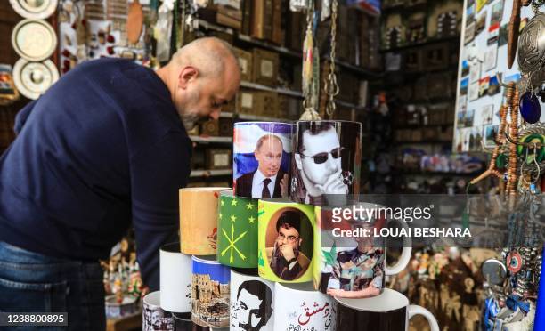 Souvenir shop owner displays objects with images of Syrian President Bashar al-Assad, Russian President Vladimir Putin and head of the Lebanese...