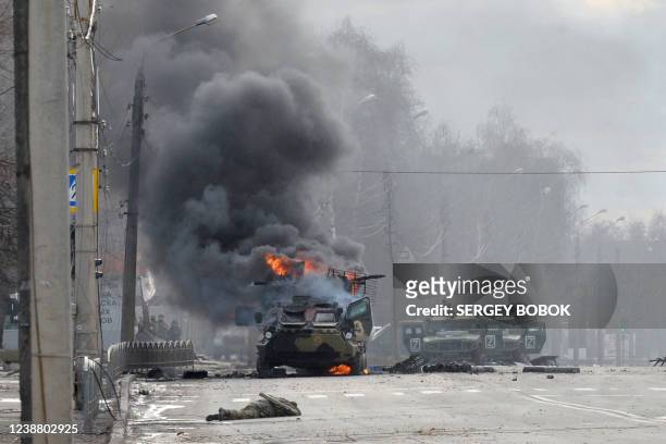 An unidentified soldier's body lies near a burning Russian Armoured personnel carrier during fighting with the Ukrainian armed forces in Kharkiv, on...
