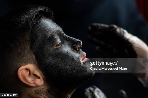 Boy gets his face covered with oil and soot as he prepares for representing a devil during a traditional carnival festival. Every year, the small...