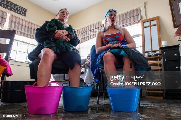 Swimmers dip their feet in warm water while sitting in a warming hut after swimming in the 200 meter freestyle race during the Memphremagog Winter...