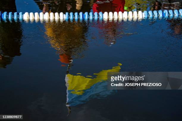 Ukrainian flag is reflected in the ice covered water during the Memphremagog Winter Swimming Festival in Newport, Vermont, on February 26, 2022. -...