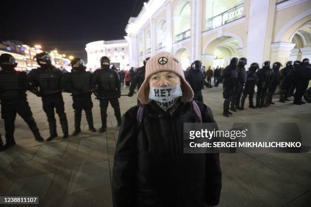 Demonstrator wearing a face mask with an inscription reading "No to war" stands in front of a line of police officers during a protest against...