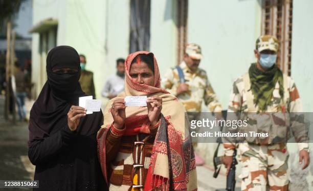 Muslim and a Hindu woman show their voting slips before casting their votes at a polling booth during the fifth phase of Uttar Pradesh assembly...