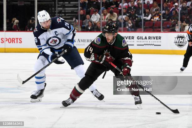Shayne Gostisbehere of the Arizona Coyotes skates with the puck while being defended by Blake Wheeler of the Winnipeg Jets during the second period...