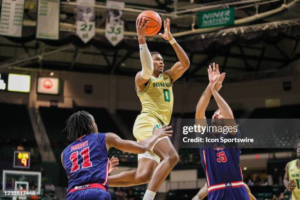 Clyde Trapp of the Charlotte 49ers shoots the ball over Dardan Kapiti and Michael Forrest of the Florida Atlantic Owls during a basketball game...