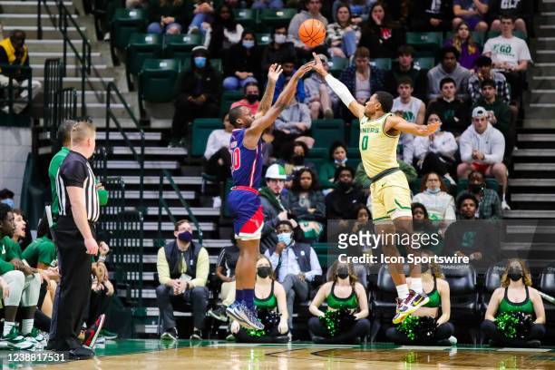 Clyde Trapp of the Charlotte 49ers tries to block three point attempt by Johnell Davis of the Florida Atlantic Owls during a basketball game between...