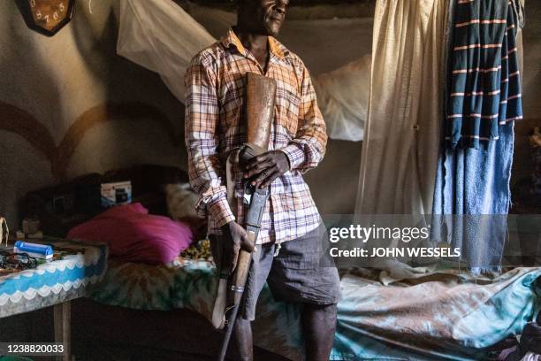 Hunter poses for a portrait with his long barrel hunting gun on the outskirts of Bopolu on November 15, 2021. - Pangolins, scale-covered...