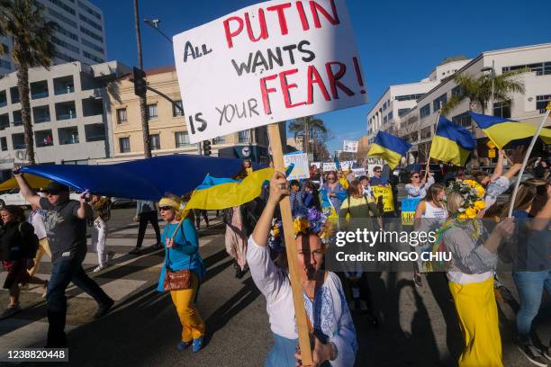 Demonstrators march during a rally in support of Ukraine, in Santa Monica, California, on February 27, 2022. - Dressed in the blue and yellow of...