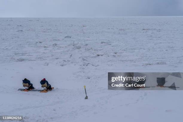 People keep warm in sleeping bags as they sit in chairs to view drift ice on the Sea of Okhotsk on February 23, 2022 in Shari, Japan. The temperature...