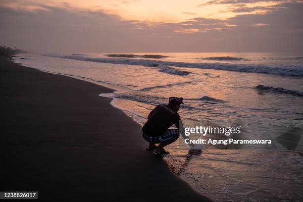 Balinese man takes sea water using plastic jerrycan during Melasti Ritual prior to Nyepi Day on February 27, 2022 on a beach in Gianyar, Bali,...