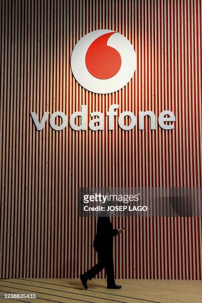 Visitor walks past a Vodafone logo on the opening day of the MWC in Barcelona on February 28, 2022. - The world's biggest mobile fair is held from...