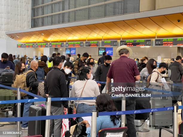 Passengers stand in line at the Japan Airlines ticket counter at Los Angeles International Airport in Los Angeles, California, on February 28, 2022.