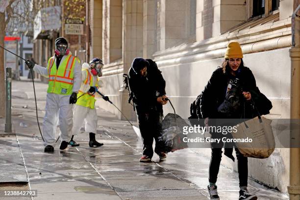 People have to move their belongings as San Francisco Public Works pressure washes the sidewalk along Eddy St. In the Tenderloin district of downtown...