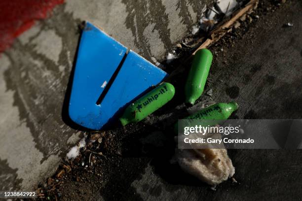 Nitrous oxide cannisters used to get high lie in the street as San Francisco Public Works pressure washes the sidewalk along Van Ness Ave. In the...