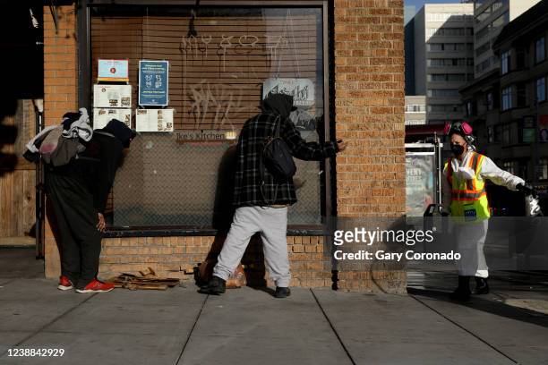Two men who are doing illegal drugs are asked to move while San Francisco Public Works pressure washes the sidewalk along Van Ness Ave. In the...