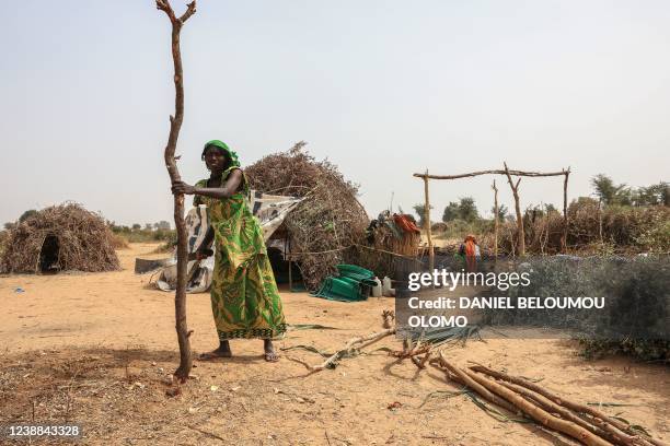 Refugee woman holds a pole she will use to built a shelter at the Bogo refugee camp in Maroua on January 17, 2022. - Thousands of people have taken...