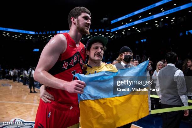 Svi Mykhailiuk of the Toronto Raptors poses with a fan and a Ukrainian flag after the Toronto Raptors' win against the Brooklyn Nets at Barclays...