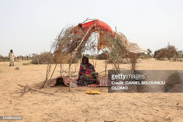 Refugee woman sits inside the skeleton of a shelter at the Bogo refugee camp in Maroua on January 17, 2022. - Thousands of people have taken refuge...