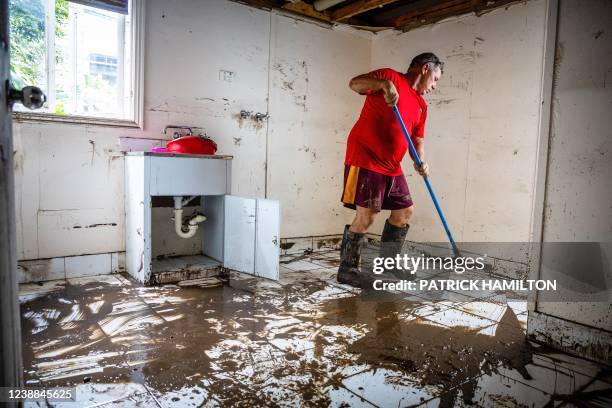 Man clears mud from the lower level of a home following flooding in the suburb of Newmarket in Brisbane on March 1, 2022.