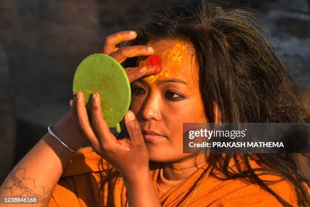 Sadhu or Hindu holy woman applies paint on her face at the Pashupatinath temple on the occasion of Maha Shivaratri festival in Kathmandu on March 1,...