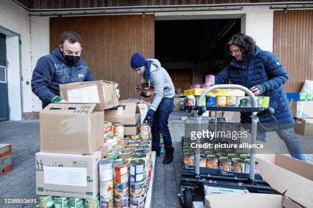 March 2022, Bavaria, Moosinning: Helpers pack a europallet with food for an aid transport of the organization "Helferschweine". The aid supplies are...