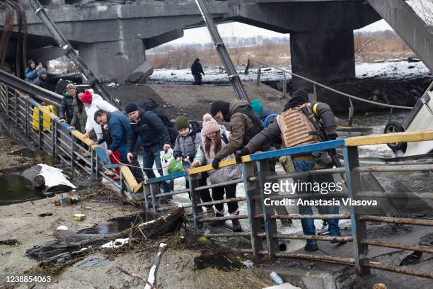People cross the destroyed bridge across the Irpin river on March 1, 2022 in Irpin, Ukraine. Russian forces continued to advance on the Ukrainian...