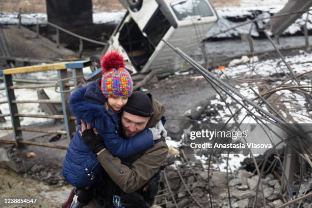 Ukrainian serviceman helps a child to cross the destroyed bridge on March 1, 2022 in Irpin, Ukraine. Russian forces continued to advance on the...