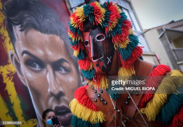 Masked reveller, dressed up as a "Careto", walks past a mural depicting Manchester United's Portuguese forward Cristiano Ronaldo during a traditional...