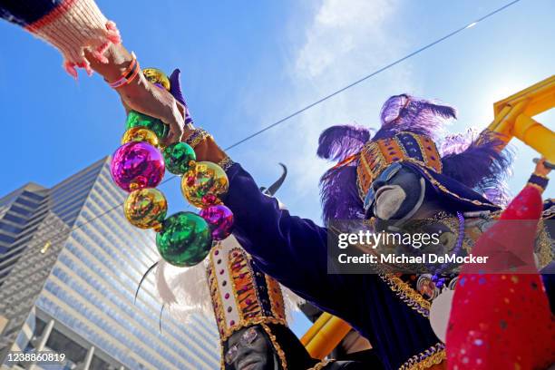 Float rider hands out a string of beads as the 1,500 members of the Krewe of Zulu make their way down St. Charles Avenue on Mardi Gras Day with their...
