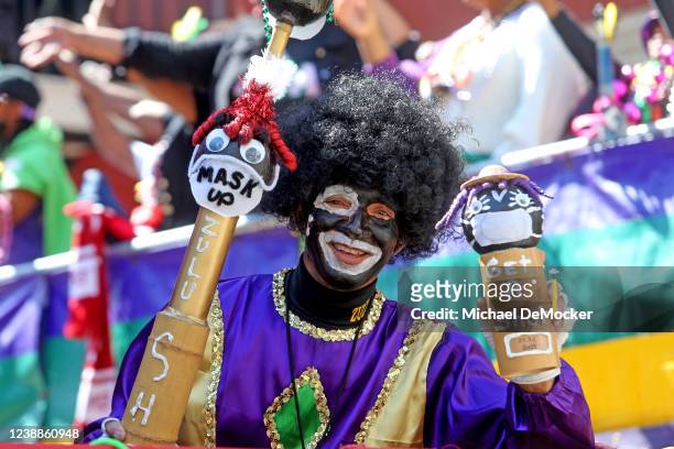 Rider holds up hand-decorated coconuts promoting masking and vaccination as the 1,500 members of the Krewe of Zulu make their way down St. Charles...