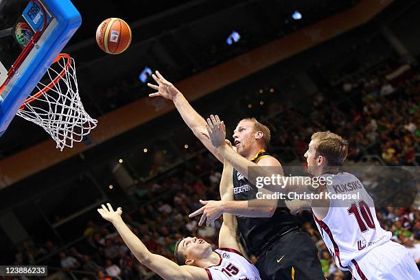 Andrejs Selakovs and Rihards Kuksiks of Latvia defend against Chris Kaman of Germany during the EuroBasket 2011 first round group B match between...