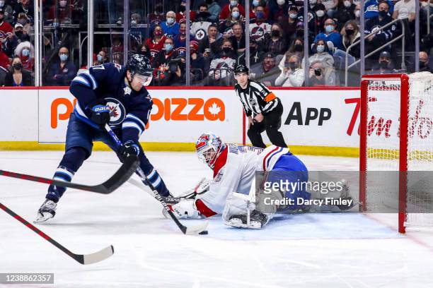 Adam Lowry of the Winnipeg Jets plays the puck around a sprawling Sam Montembeault of the Montreal Canadiens for a first period goal at the Canada...