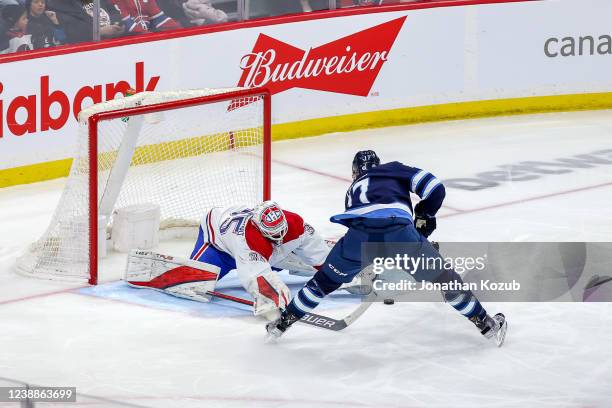 Adam Lowry of the Winnipeg Jets plays the puck around a sprawling Sam Montembeault of the Montreal Canadiens for a first period goal at the Canada...