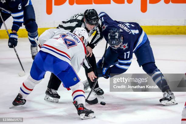 Adam Lowry of the Winnipeg Jets wins a first period face-off against Nick Suzuki of the Montreal Canadiens at the Canada Life Centre on March 1, 2022...