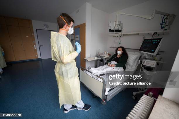 February 2022, Baden-Wuerttemberg, Stuttgart: Gregor Paul , senior physician, talks to patient Ioanna Maag-Nikolopoulou in a patient room of a Covid...