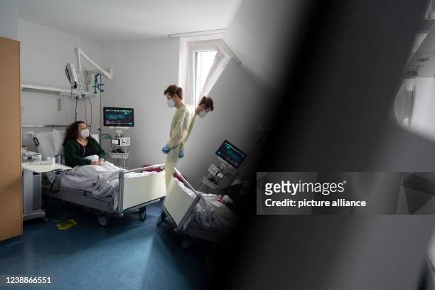 February 2022, Baden-Wuerttemberg, Stuttgart: Gregor Paul , senior physician, talks to patient Ioanna Maag-Nikolopoulou in a patient room of a Covid...