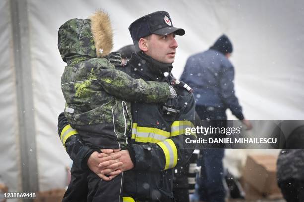 Romanian fireman carries a refugee child coming from Ukraine at the Ukrainian-Romanian border in Siret on March 02, 2022. - Refugees from Ukraine...