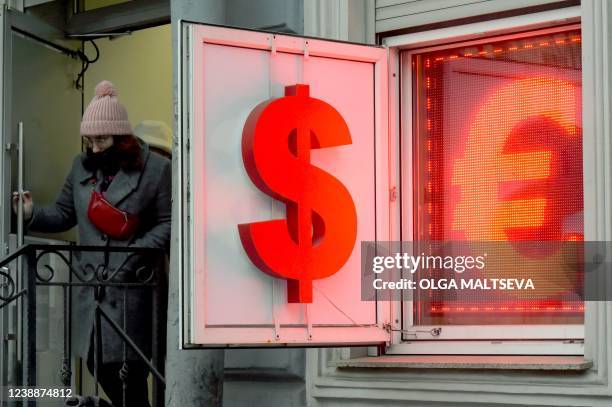 Woman leaves a currency exchange office displaying the US dollar and the euro signs in Saint Petersburg on March 2022. - Russian authorities are...