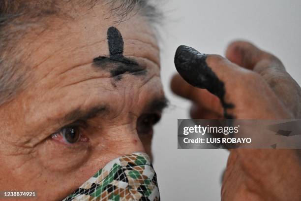 Catholic faithful gets the symbol of the cross marked with ash on her forehead during the celebration of Ash Wednesday, the first day of Lent, in...