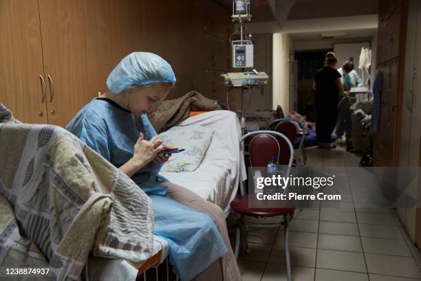 Nurse eyes her smartphone in a bomb shelter as children and their relatives wait to evacuate the Ohmatdyt children's hospital and head to Poland by...