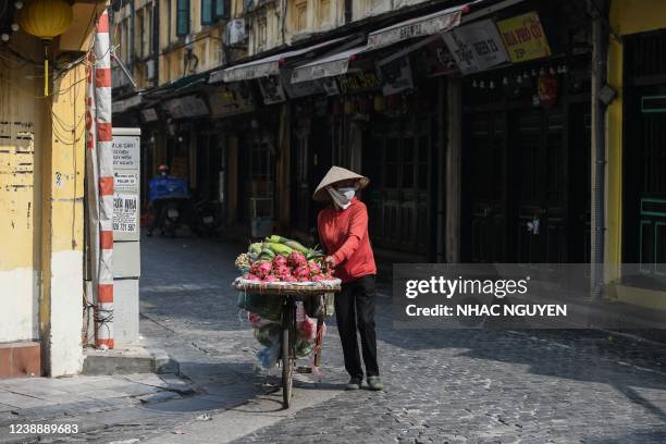Fruit vendor pushes her bicycle on a street in Hanoi on March 3, 2022.